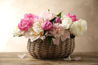 Beautiful peony bouquet in wicker basket on wooden table