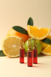 Skincare ampoules with vitamin C, different citrus fruits and leaves on beige background