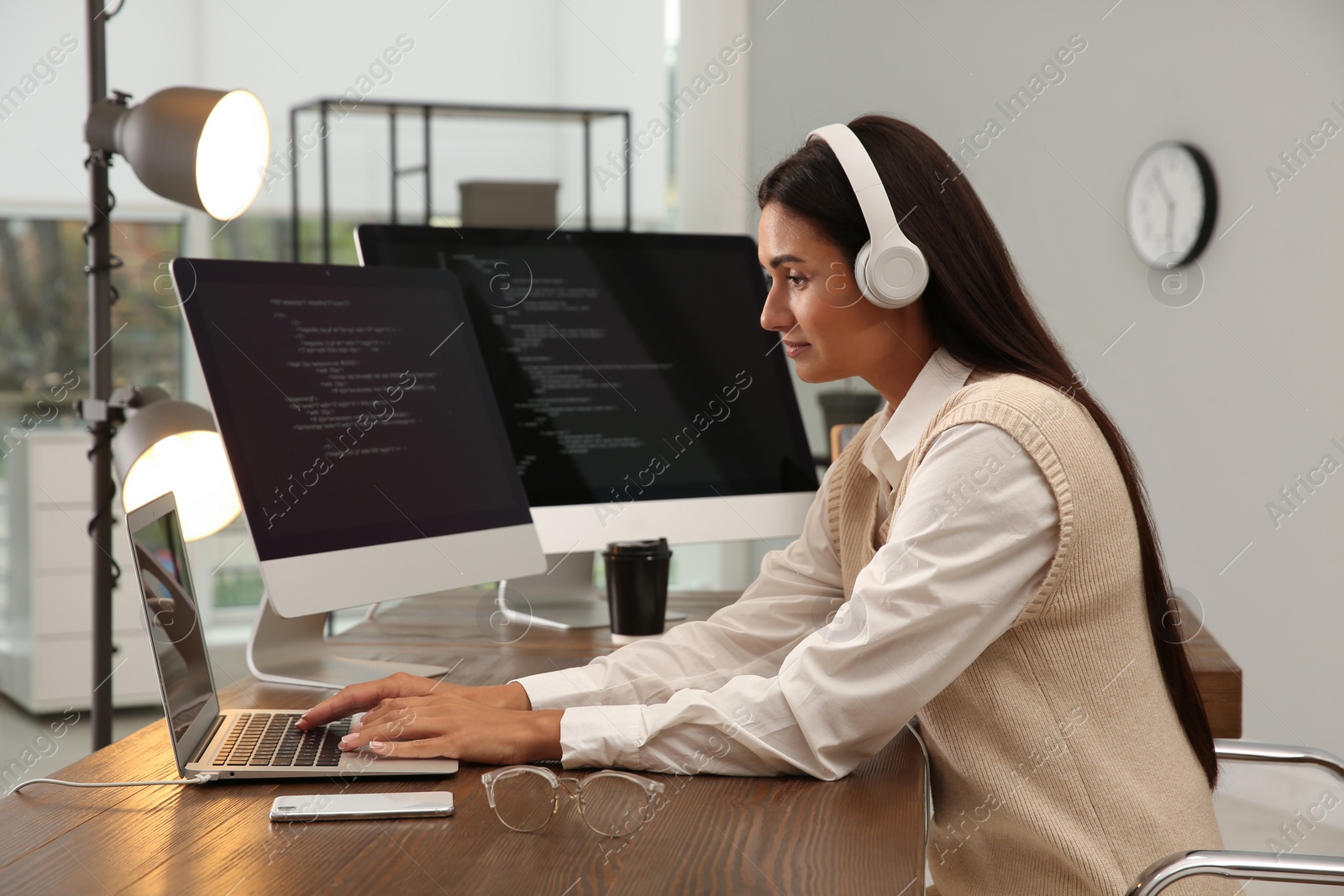 Photo of Programmer with headphones working at desk in office