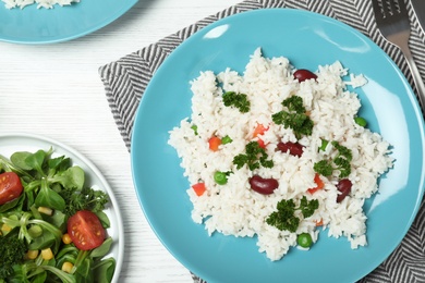 Photo of Boiled rice with vegetables served on wooden table, flat lay