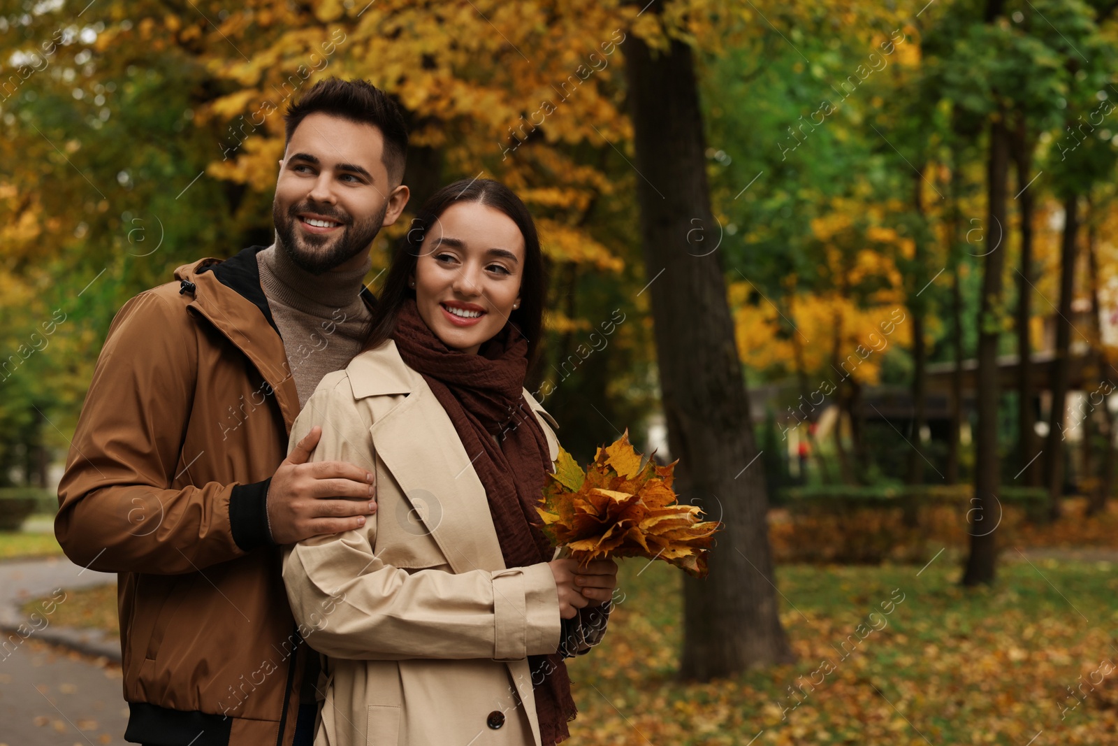 Photo of Romantic young couple spending time together in autumn park, space for text