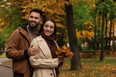 Romantic young couple spending time together in autumn park, space for text