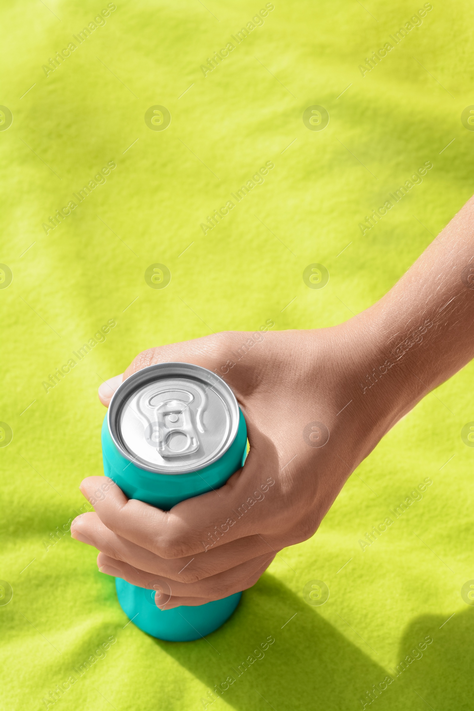 Photo of Woman holding aluminum can with beverage on yellow blanket, closeup