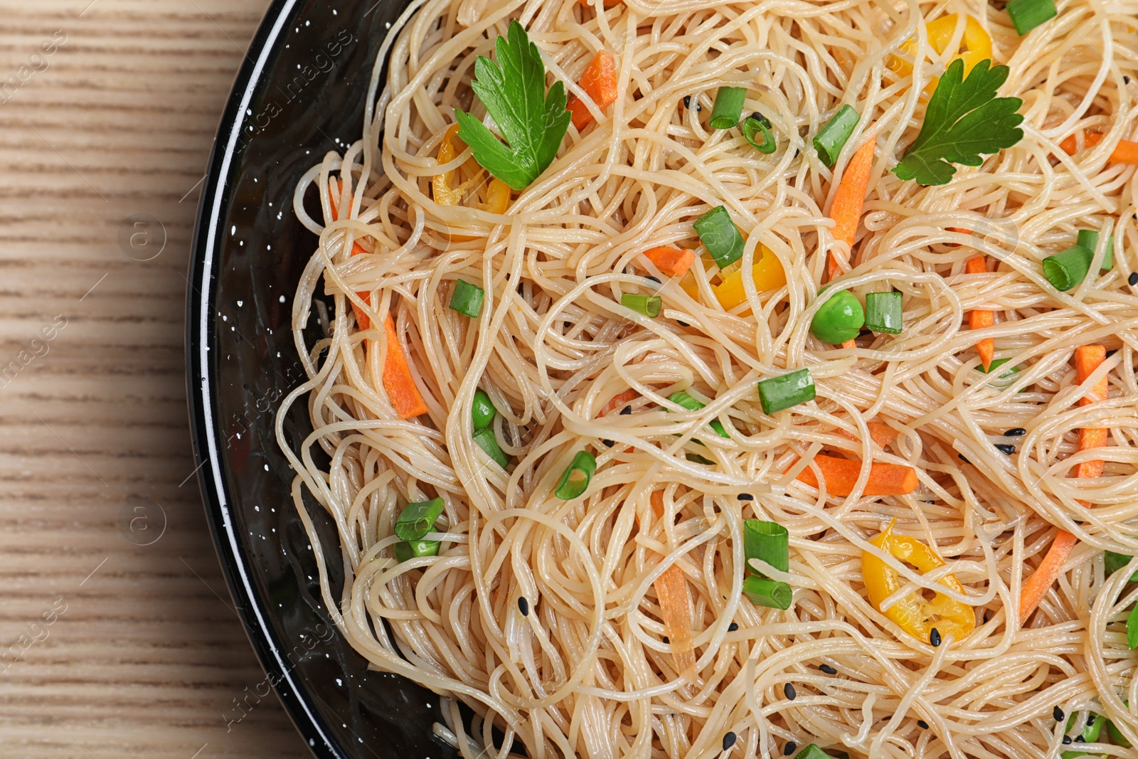 Photo of Top view of pan with delicious asian noodles and vegetables on table, closeup