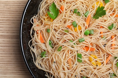 Photo of Top view of pan with delicious asian noodles and vegetables on table, closeup