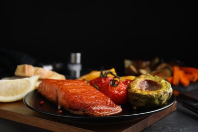 Delicious cooked salmon and vegetables on black table, closeup. Healthy meals from air fryer
