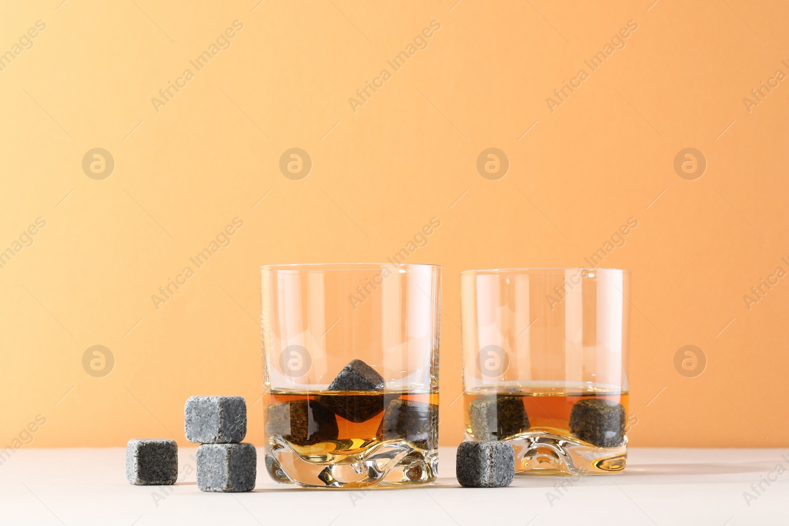 Photo of Whiskey stones and drink in glasses on light table