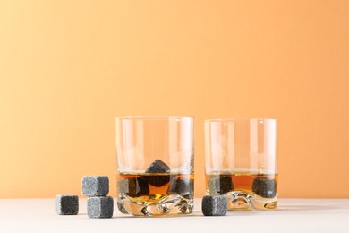 Whiskey stones and drink in glasses on light table