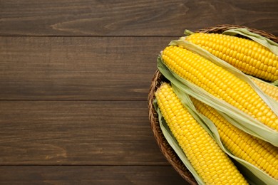 Tasty fresh corn cobs on wooden table, top view. Space for text