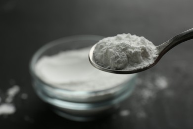 Photo of Spoon of baking powder over bowl, closeup. Space for text