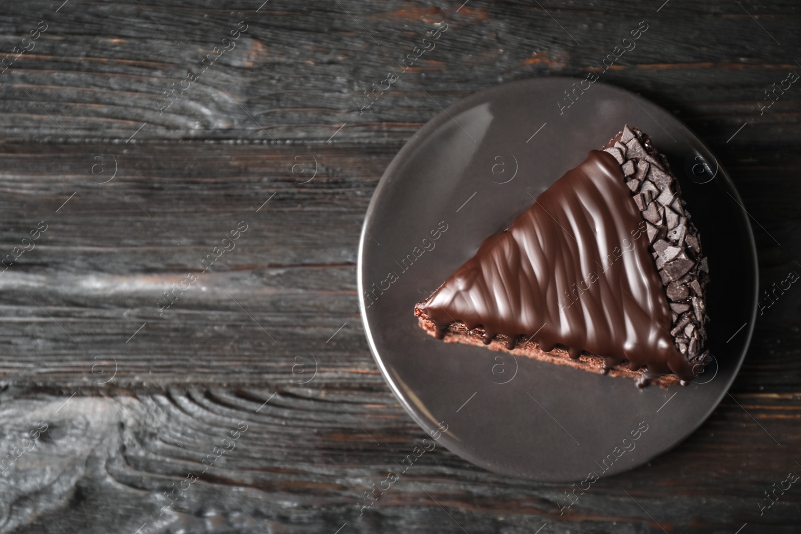 Photo of Delicious chocolate cake on black wooden table, top view. Space for text