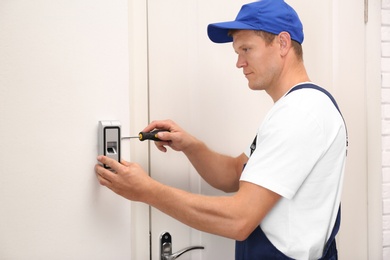 Male technician installing fingerprint security alarm system indoors