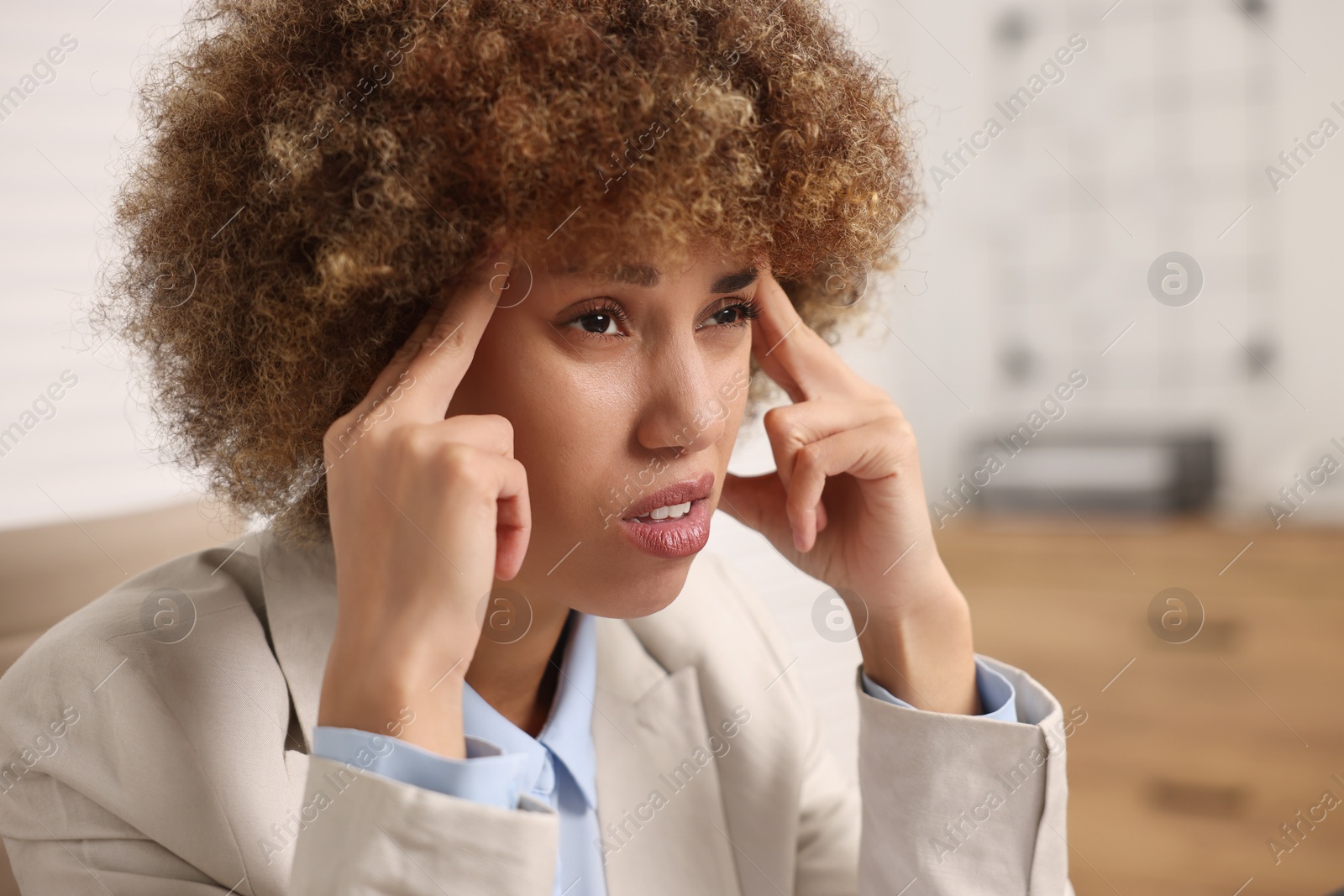 Photo of Young woman suffering from headache in office