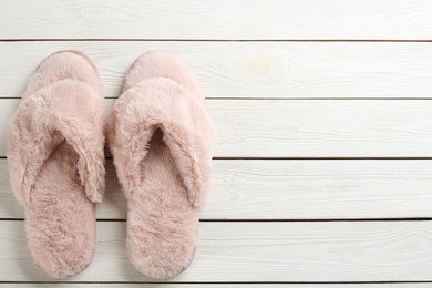 Photo of Pair of stylish soft slippers on white wooden background, flat lay. Space for text