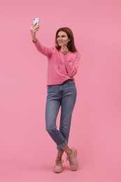 Photo of Beautiful woman taking selfie on pink background