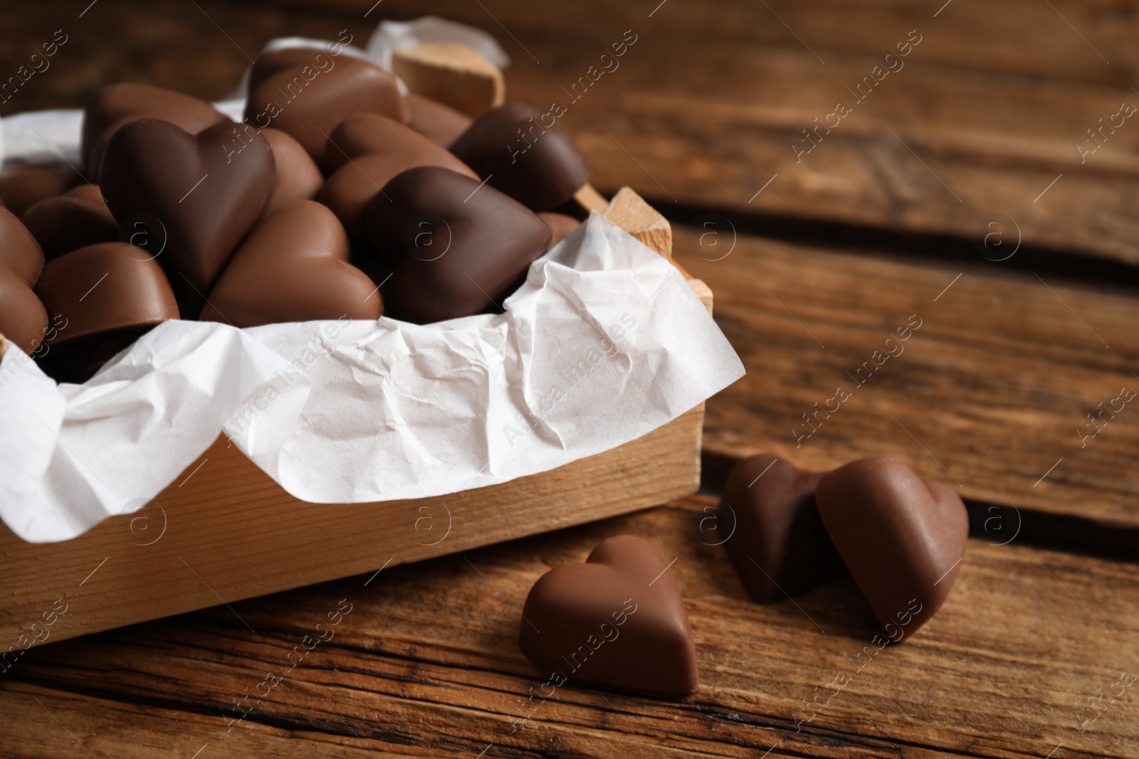 Photo of Delicious heart shaped chocolate candies on wooden table