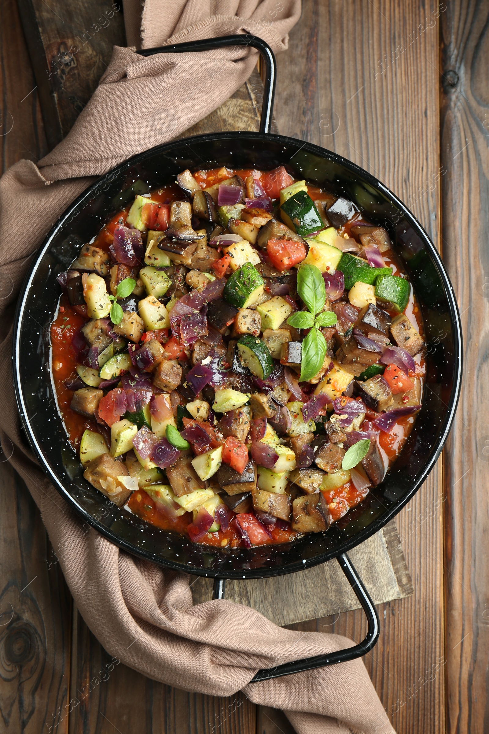 Photo of Delicious ratatouille in baking dish on wooden table, top view