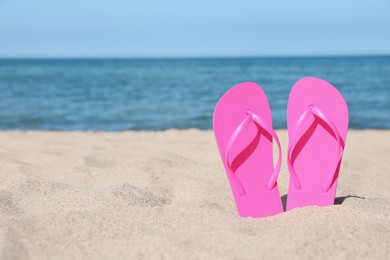 Stylish pink flip flops on beach sand, space for text