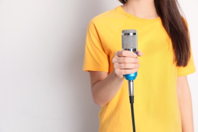 Photo of Young woman holding microphone on color background. Space for text