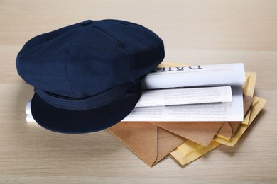 Photo of Blue postman's hat, envelopes and newspapers on wooden table