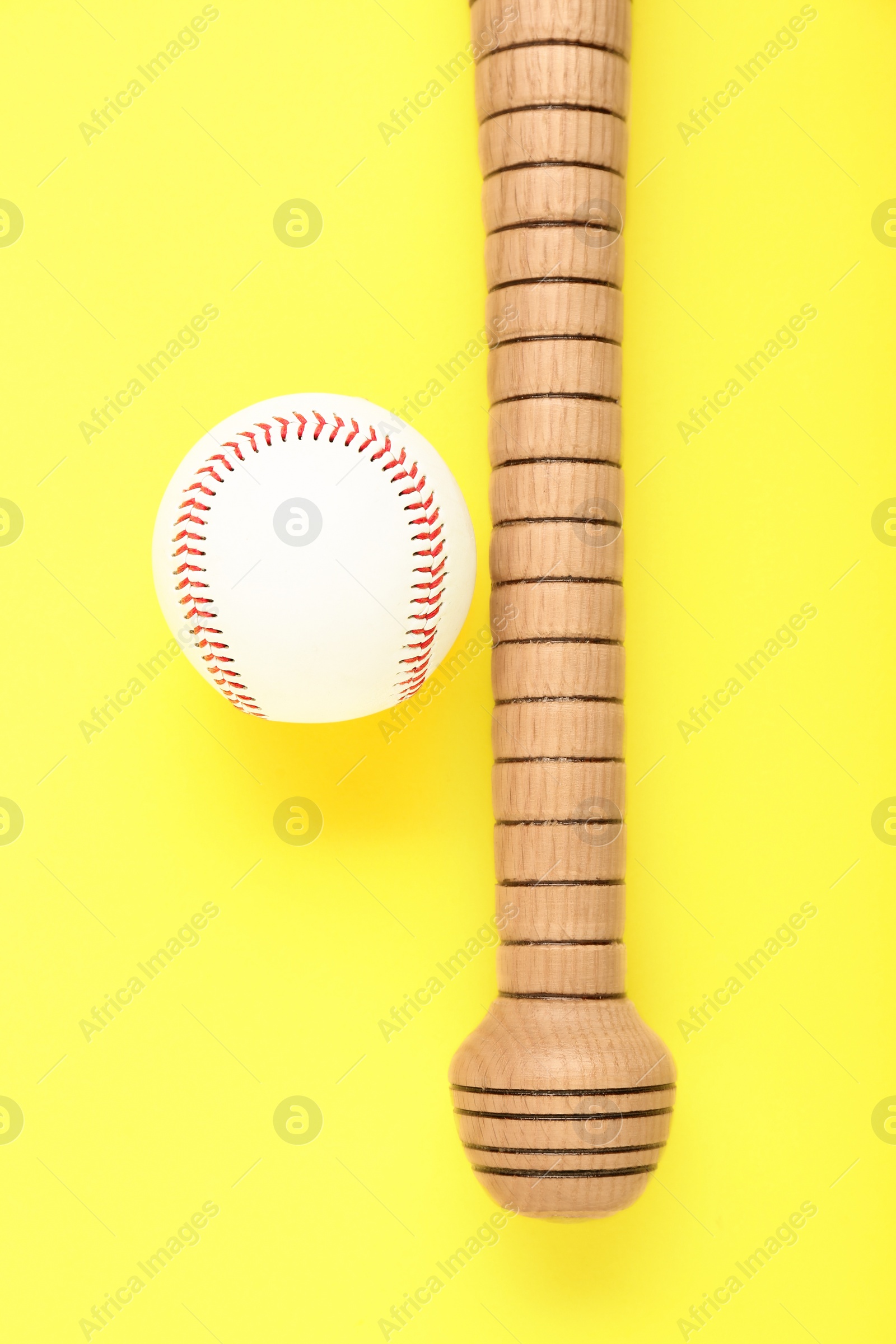 Photo of Wooden baseball bat and ball on yellow background, flat lay. Sports equipment