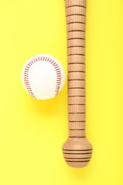 Photo of Wooden baseball bat and ball on yellow background, flat lay. Sports equipment