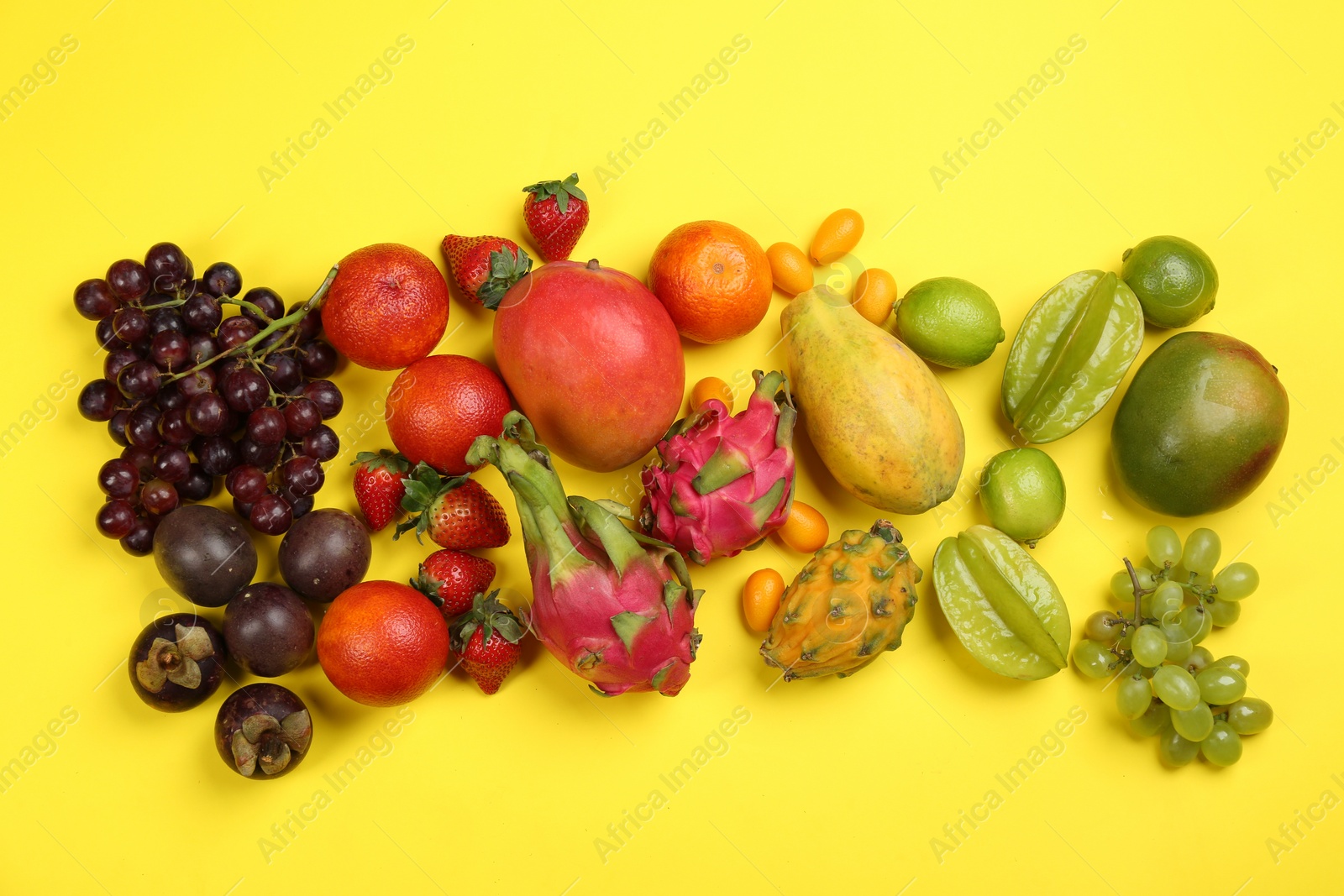 Photo of Assortment of fresh exotic fruits on yellow background, flat lay