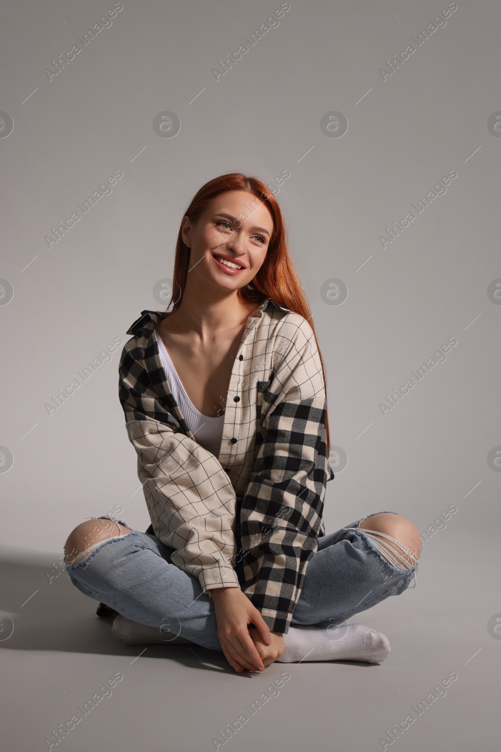 Photo of Beautiful young woman sitting on gray background