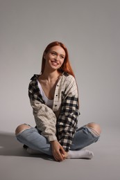 Photo of Beautiful young woman sitting on gray background