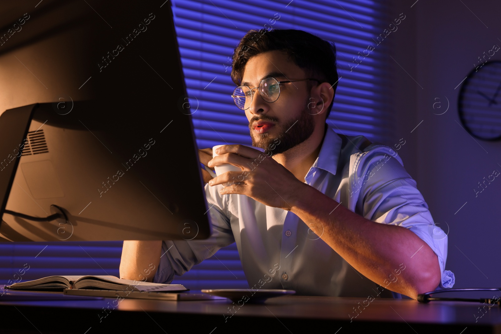 Photo of Tired man with coffee working late in office