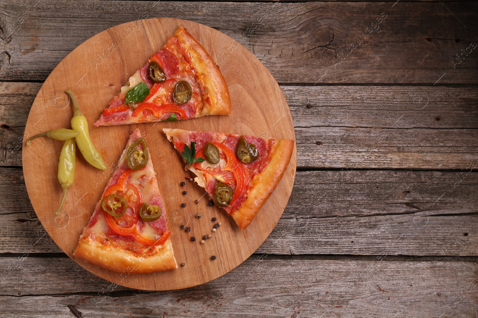 Photo of Pieces of delicious pizza Diablo, pickled peppers and spices on wooden table, top view. Space for text