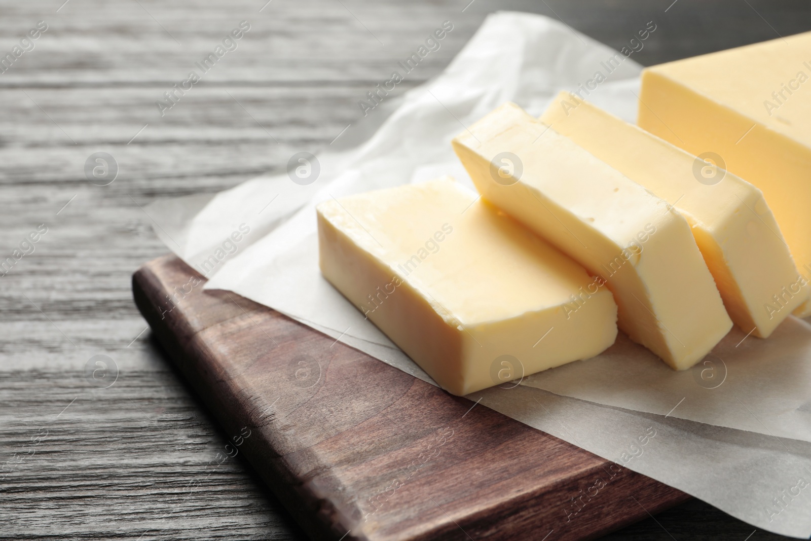 Photo of Wooden board with fresh butter on table. Space for text