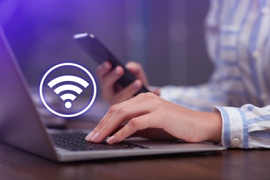 Image of Woman using smartphone and laptop connected to WiFi at wooden table indoors, closeup