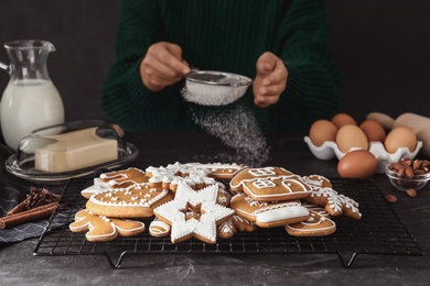 Photo of Woman cooking at grey table, focus on delicious homemade Christmas cookies