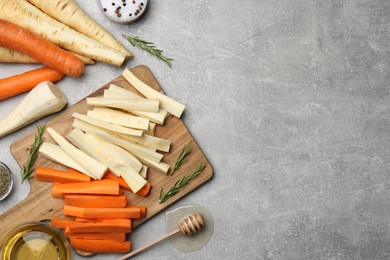 Photo of Flat lay with parsnips, carrots and other products on light grey table. Space for text