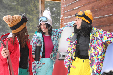 Friends with skis and snowboards wearing winter sport clothes outdoors
