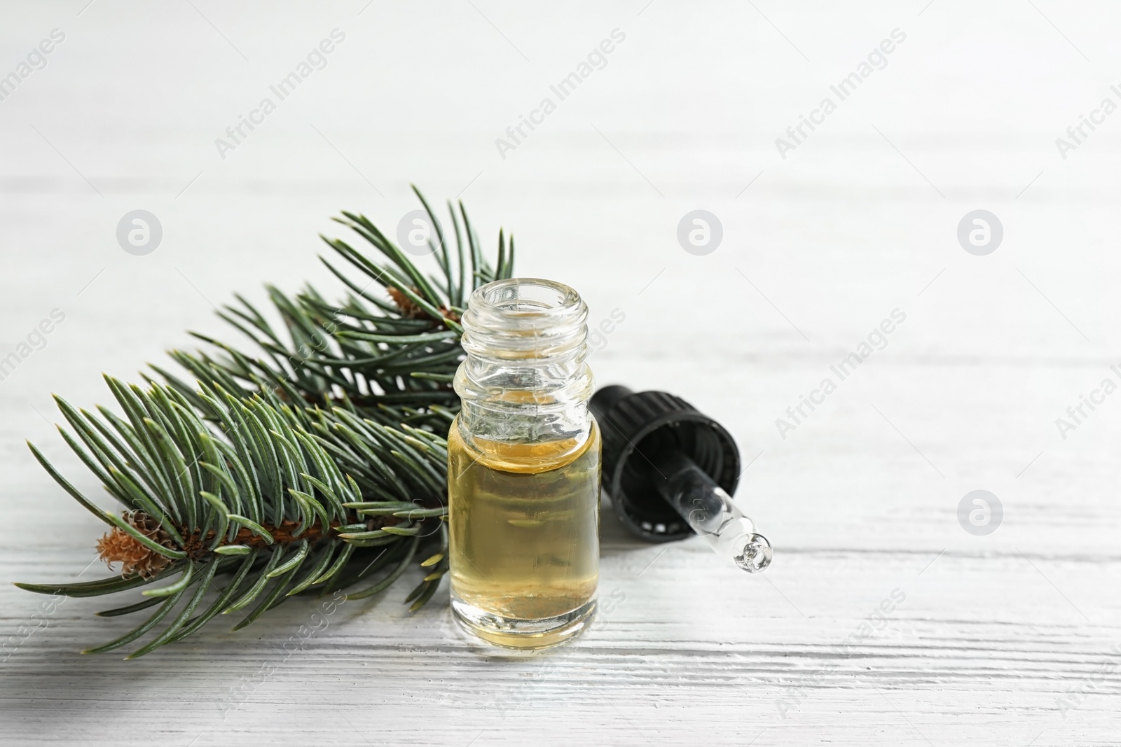 Photo of Composition with bottle of conifer essential oil on white wooden background. Space for text