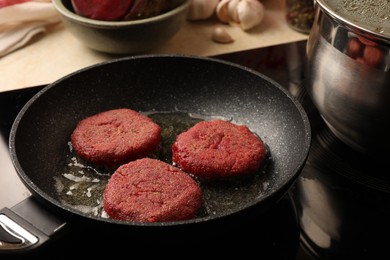 Cooking vegan cutlets in frying pan on stove, closeup