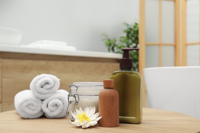 Different spa products and beautiful flower on wooden table in bathroom