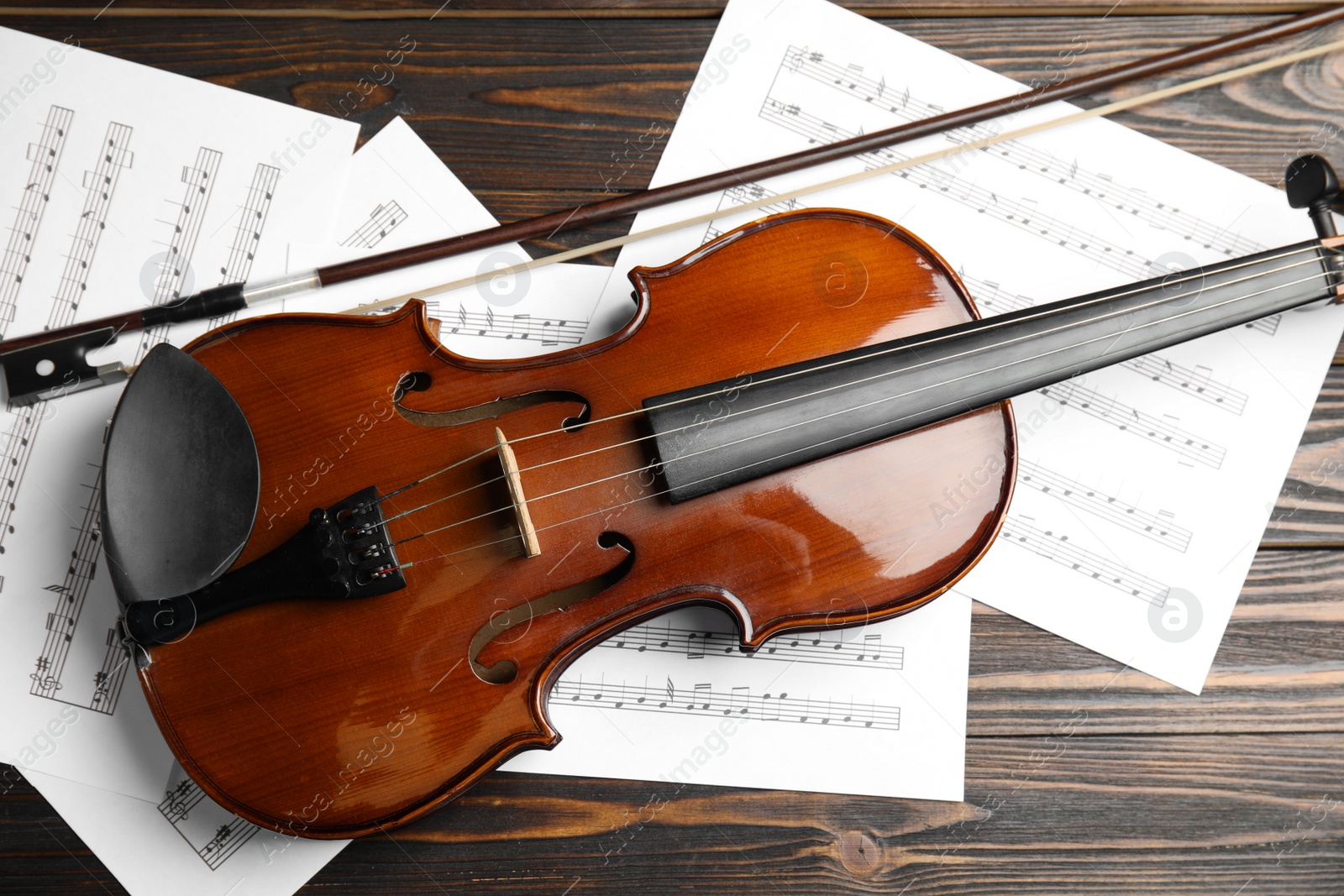 Photo of Beautiful violin, bow and note sheets on wooden table, flat lay