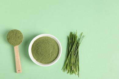 Photo of Wheat grass powder and fresh sprouts on green table, flat lay