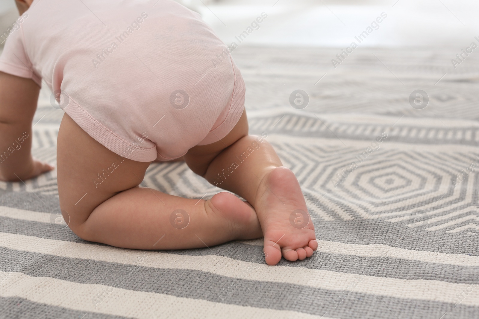 Photo of Baby crawling on floor at home, closeup