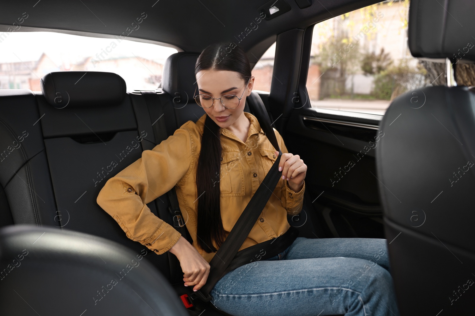 Photo of Woman fastening safety seat belt inside modern car