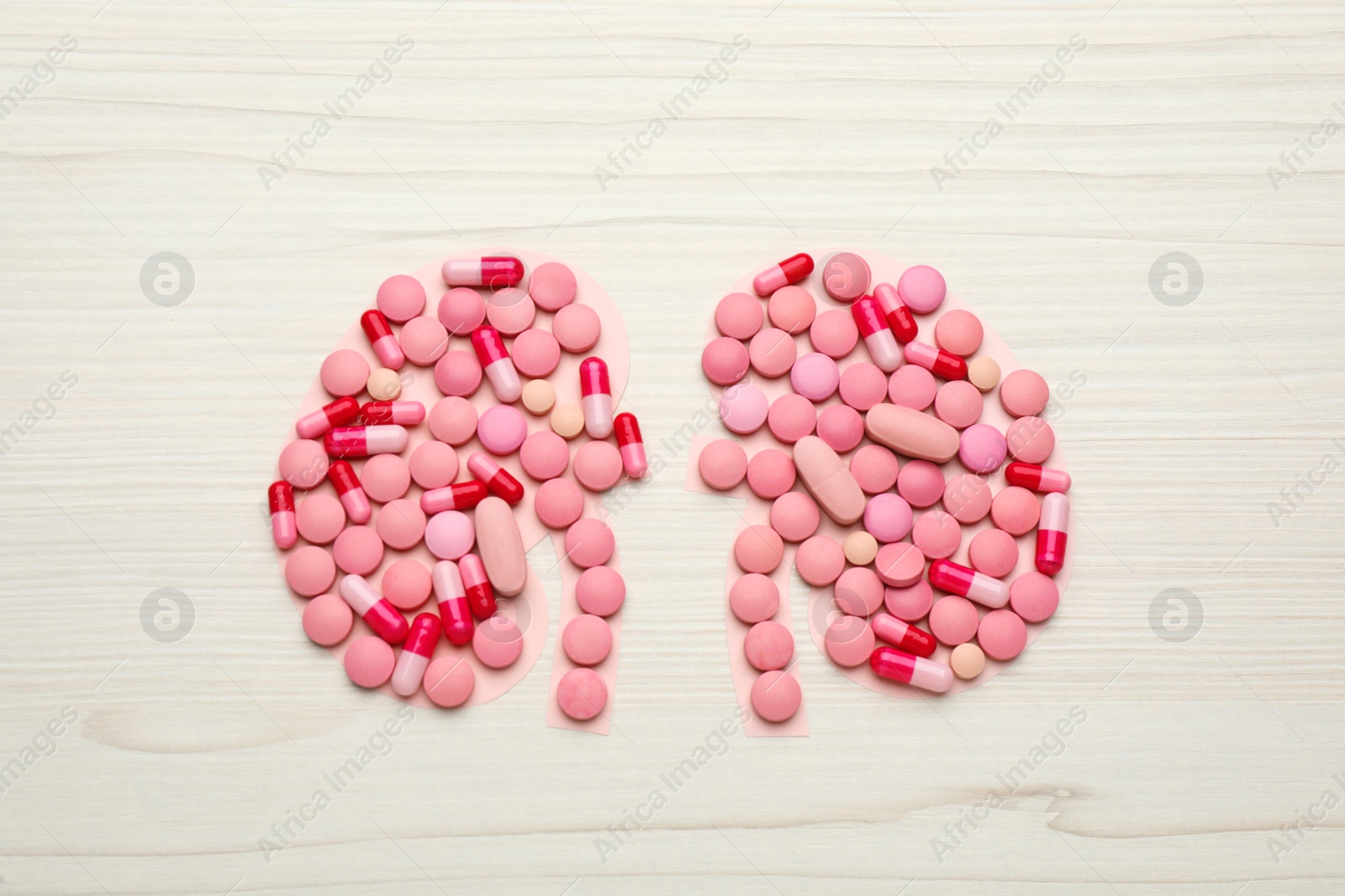 Photo of Kidneys shape of pills on white wooden table, flat lay