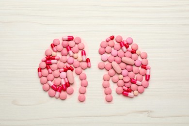 Kidneys shape of pills on white wooden table, flat lay