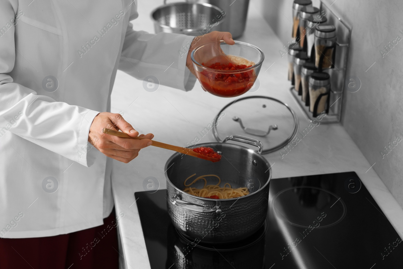 Photo of Professional chef cooking delicious pasta in saucepan indoors, closeup