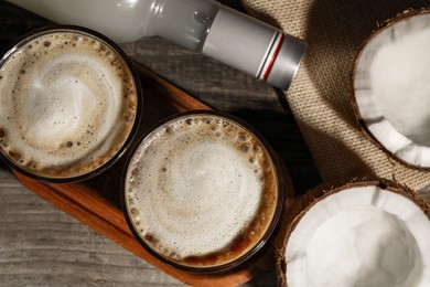 Glasses of tasty coffee with coconut syrup on wooden table, flat lay