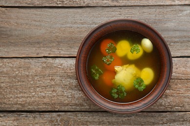 Photo of Delicious chicken bouillon with parsley, carrot and eggs on wooden table, top view. Space for text