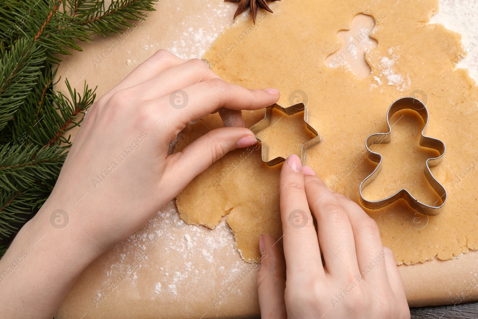 Photo of Woman making Christmas cookies with cutters at table, top view