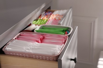 Photo of Open cabinet drawers with menstrual pads, tampons and pantyliners indoors, closeup